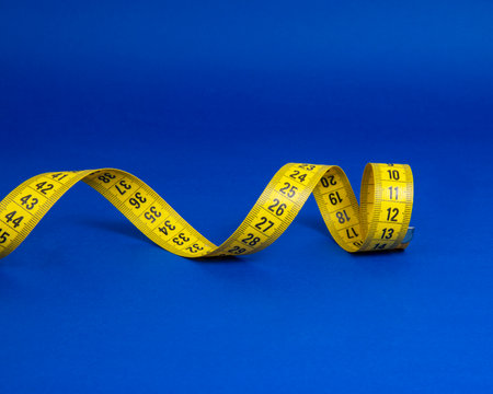 Yellow spiral tape measure on dark blue background