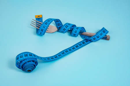 Metal fork and blue tape measure on blue backgroundの写真素材