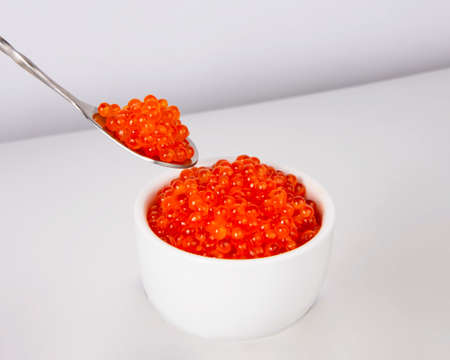 Red caviar in silver spoon isolated on the white backgroundの写真素材