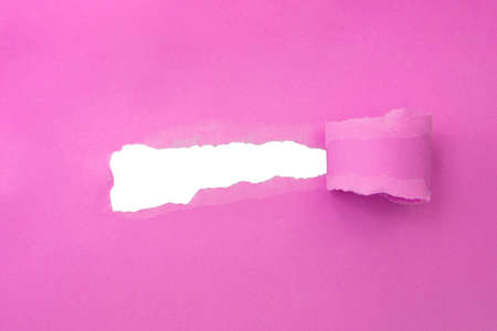 Hole in paper pink color background damaged rippedの写真素材