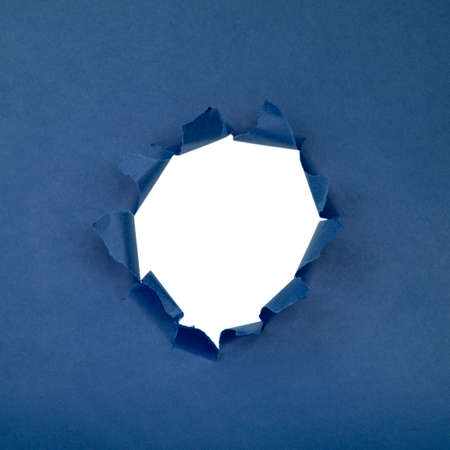 Hole in paper blue background torn damaged for designの写真素材