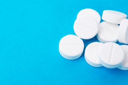 Heap of round white pills on blue background