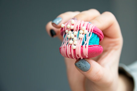 Female hands holding colorful french macaroonsの写真素材