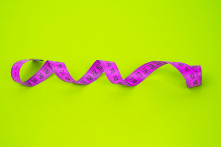 Pink measuring tape on a green background. The concept of diet and weight loss.の写真素材