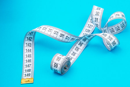 White measure tape on blue backgrond with copyspace