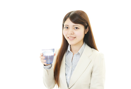 A young woman drinking a glass of waterの写真素材