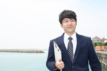Smiling Asian businessman by the seaの写真素材