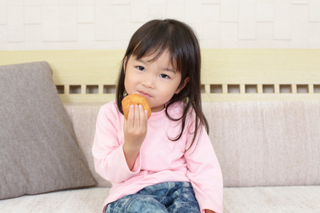 Happy girl eats a sweetの写真素材