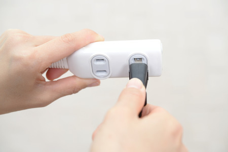 Woman holding electric plug and extension cordの写真素材