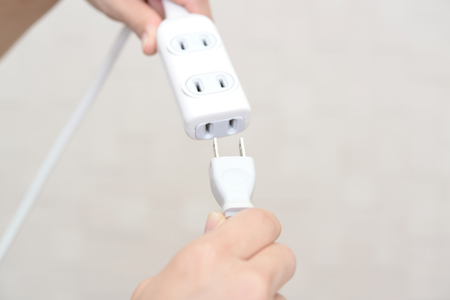 Woman holding electric plug and extension cord
