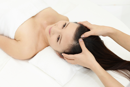 Woman in spa salon receives head massageの写真素材
