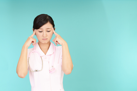 A female nurse who has a headacheの写真素材
