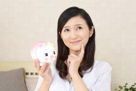Smiling young woman with a piggy bankの写真素材