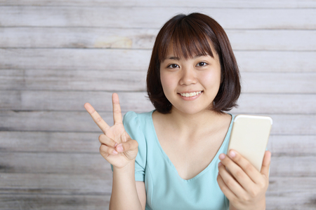 Asian teen girl with a smart phoneの写真素材