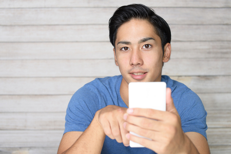 Asian man holding a smart phoneの写真素材
