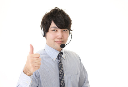 Asian telephone operator showing thumbs up signの写真素材