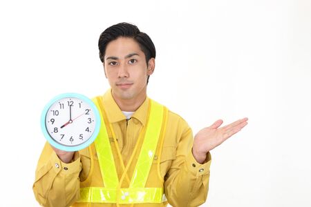 Asian worker holding a clockの写真素材
