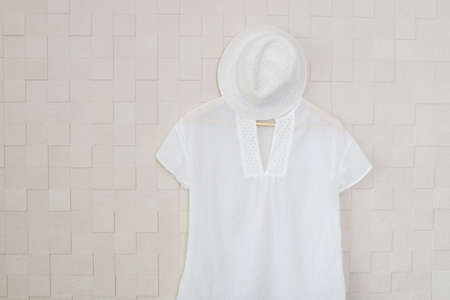 Stylish shirt and hat hanging against a wall.の写真素材