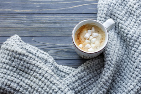 Cup of coffee with marshmallow on a wooden background. Cozy sweater.の写真素材