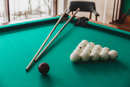 Russian billiard table with balls and cue sticks.