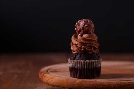 Tasty chocolate cupcakes on wooden board. Dark background