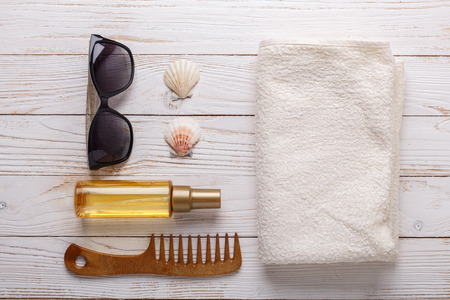 Sea accessories on wooden background Suntan oil, comb, towel, seashells, sunglasses