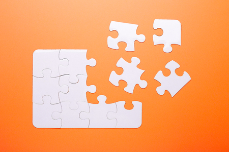 White puzzle on orange background. Missing piece. Top viewの写真素材