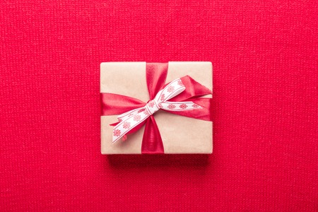 Gift box on red knitting background. Top view with copy space.