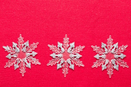 Christmas snowflakes on red knit background. Top view with copy space.