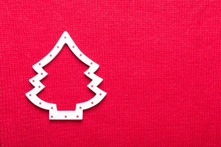 Christmas tree on red knit background. Top view with copy space.