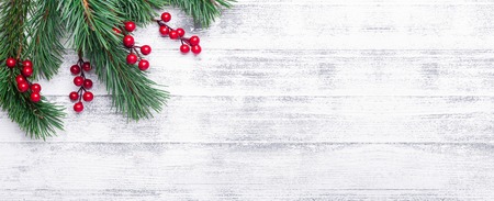 Christmas background with tree branches and holly berries. White wooden table. Top view. Copy spaceの写真素材