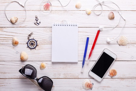 Travel vacation concept with headphones, sunglasses, smartphone, seashells, notebook and striped t-shirt. Top view with copy space. Flat layの写真素材
