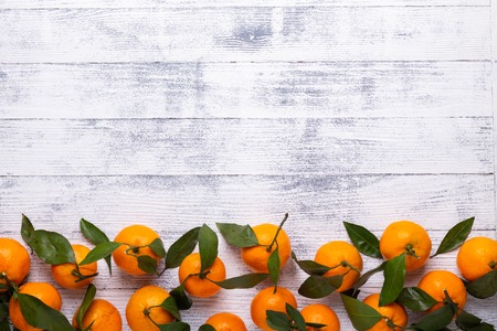 Fresh orange mandarins, tangerine with green leaves on white wooden background. Copy spaceの写真素材