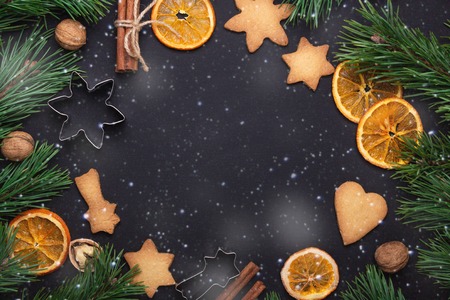 Homemade fresh cookies Fir branches Dried slices of orange Cookie cutters Christmas concept Nuts Cinnamon Top view Copy space Snow effectの写真素材
