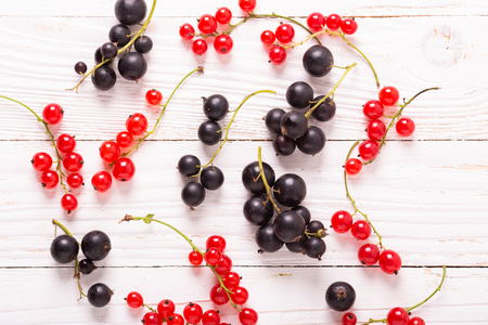 Fresh red and black currant on a white wooden background Top view Healthy foodの写真素材