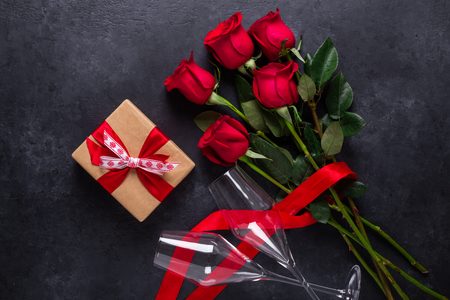 Red rose flowers bouquet, gift box, champagne glasses on black stone background Valentine's day greeting card Copy space Top viewの写真素材