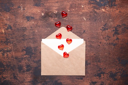 Craft envelope with red hearts on a vintage wooden background Piece of paper Valentine day concept...