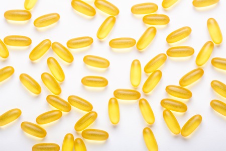 Omega 3 capsules on white background Fish oil Yellow softgels Vitamin D, E, A supplement Concept of healthcare Top view, flat lay, copy spaceの写真素材