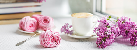 Bouquet of lilacs, cup of coffee, homemade marshmallow and stack of books on window sill Romantic...