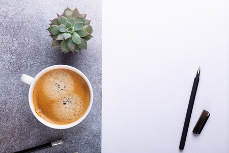 Office workplace with blank paper, cup of coffee and pen. Top view. Stone background. Copy spaceの写真素材