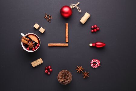 A clock in the form of spice for mulled wine. Cinnamon, anise stars, cranberries, brown sugar. Concept, creative work. Time to cook mulled wine. Top view. Black backgroundの写真素材