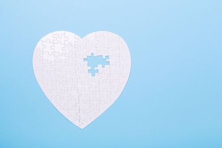White puzzle in shape of heart on blue background Concept treatment of heart disease pills Jigsaw Top view Copy spaceの写真素材