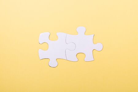 Two jigsaw puzzle pieces on yellow background White puzzle Concept success of business Top view
