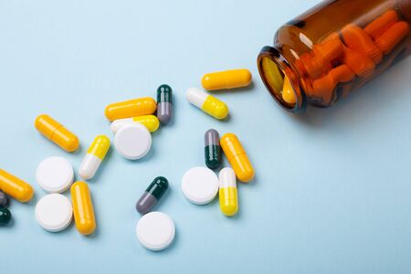 Multicolor tablets and pills capsules from glass bottle on blue background Heap of assorted various medicine tablets and pills. Health care Close-up Copy spaceの写真素材