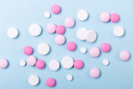 Pink and white tablets on blue background Heap of assorted various medicine tablets Health care Close-up Copy spaceの写真素材