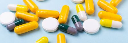 Multicolor tablets and pills capsules on blue background Heap of assorted various medicine tablets...