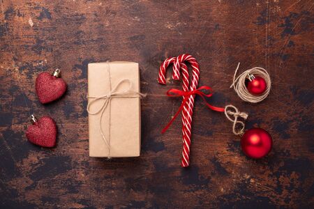 Christmas composition with candy canes, present box and gifts. Red and craft decoration on wooden background. New Year concept. Top view - Imageの写真素材