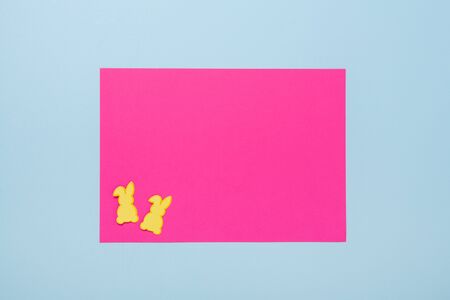Spring mockup with blank of pink paper and two bunnies on blue background. Easter concept. Copy...