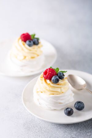 Delicious Pavlova cake with whipped cream and fresh berries on white plate. Stone background. Selective focus - Imageの写真素材