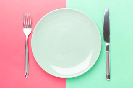 Empty mint plate, knife and fork on colored paper background Copy space Top view - Image